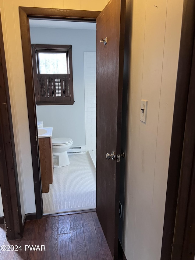 hall featuring dark wood-type flooring and a baseboard heating unit