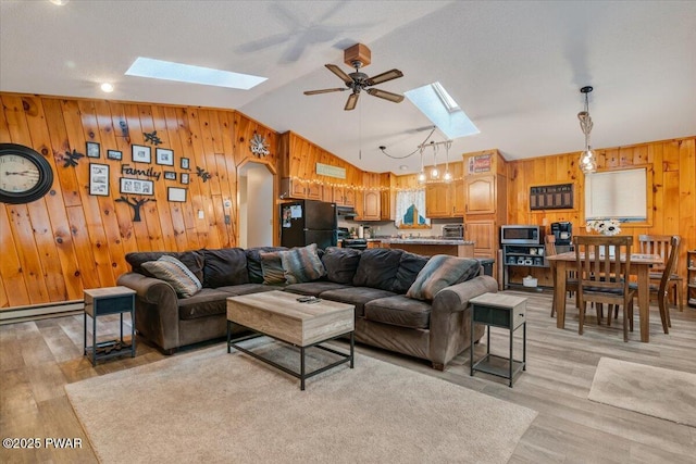 living room with light wood-type flooring, ceiling fan, vaulted ceiling with skylight, and a baseboard radiator