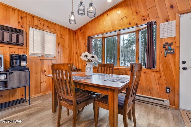 dining space featuring vaulted ceiling, an inviting chandelier, light hardwood / wood-style floors, and wooden walls