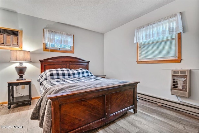 bedroom with light hardwood / wood-style flooring, a textured ceiling, and a baseboard radiator