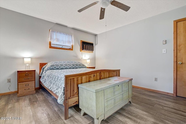 bedroom featuring ceiling fan, an AC wall unit, a textured ceiling, and hardwood / wood-style floors