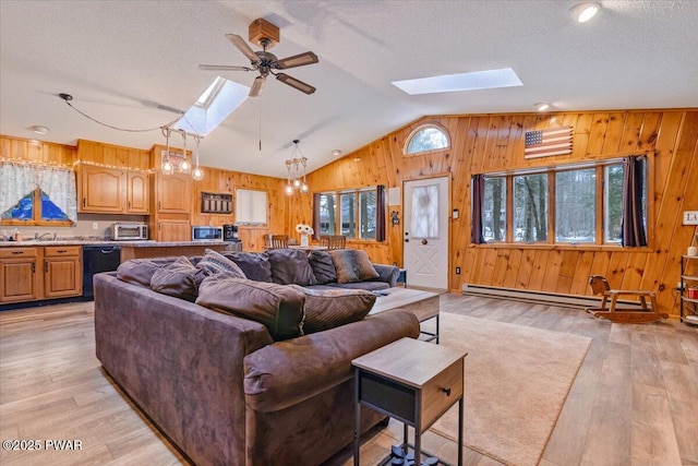 living room with a baseboard radiator, light wood-type flooring, lofted ceiling with skylight, a textured ceiling, and ceiling fan with notable chandelier