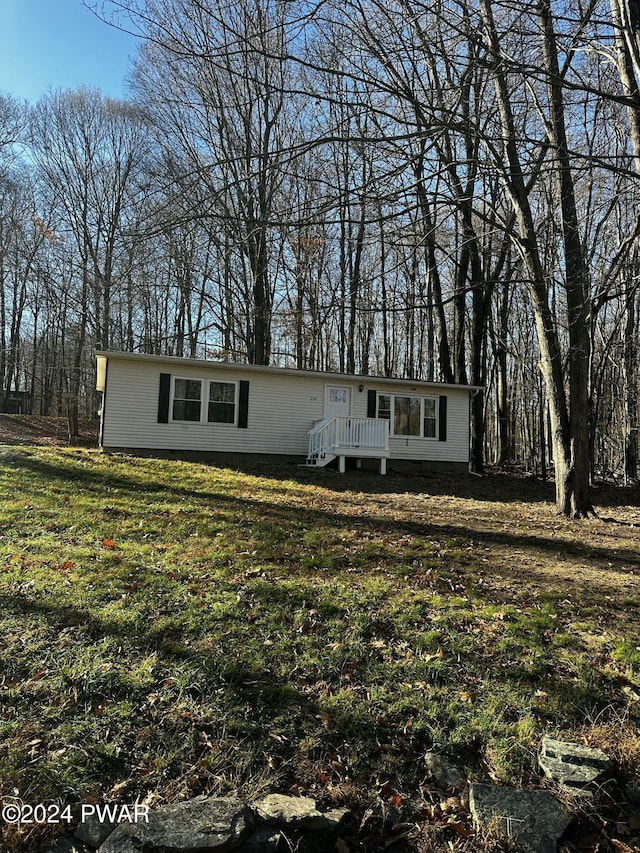 view of front facade with a wooden deck and a front lawn