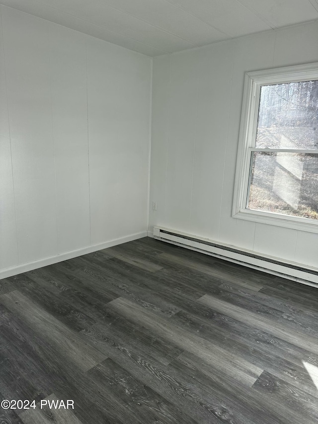 empty room featuring baseboard heating and dark wood-type flooring