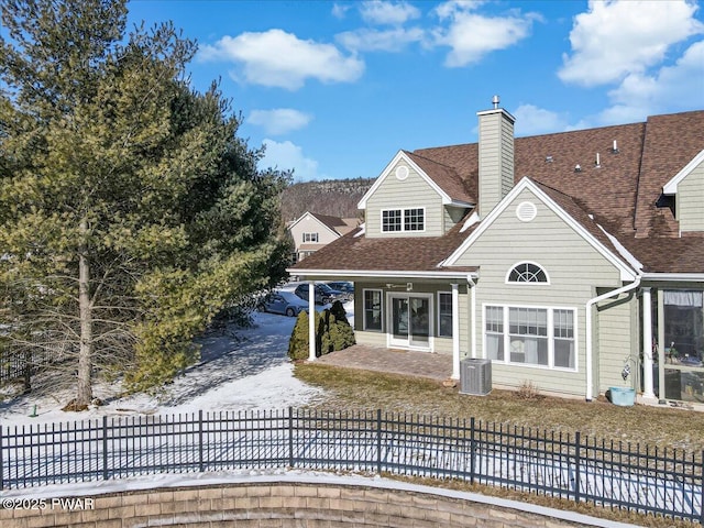 back of property featuring central air condition unit, fence private yard, a chimney, and roof with shingles