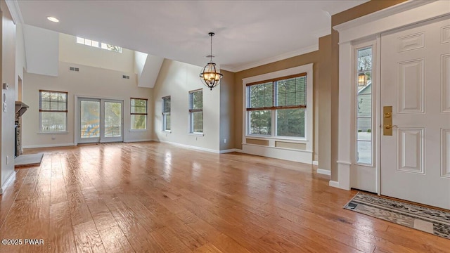 unfurnished living room featuring light wood finished floors, baseboards, visible vents, and an inviting chandelier