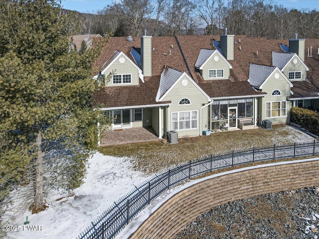 view of front of home with central AC unit, a chimney, and a fenced backyard