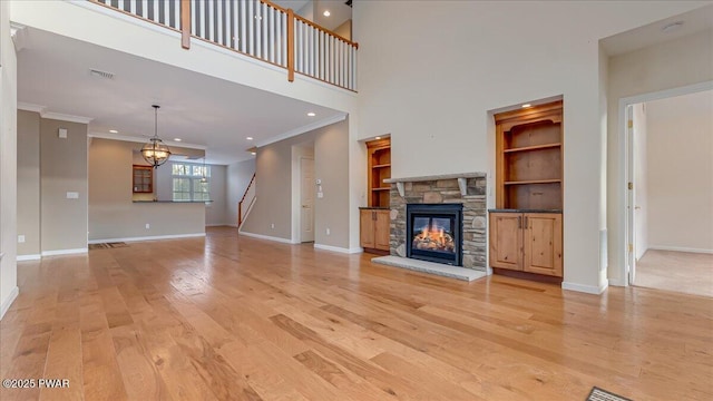 unfurnished living room with baseboards, light wood finished floors, a fireplace, and crown molding