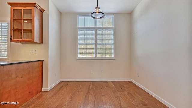 unfurnished dining area featuring light wood finished floors and baseboards