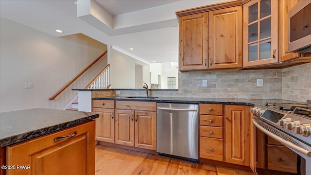 kitchen with dark stone countertops, glass insert cabinets, stainless steel appliances, and a sink