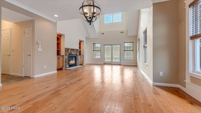 unfurnished living room with a stone fireplace, a wealth of natural light, and light wood-style flooring