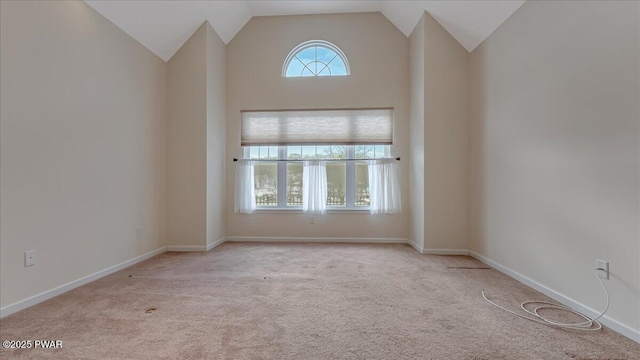 empty room featuring light carpet, high vaulted ceiling, and baseboards