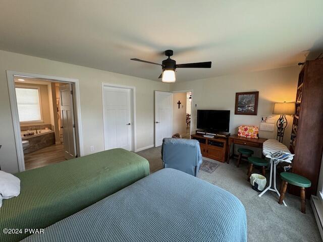 carpeted bedroom with baseboard heating, ensuite bath, and ceiling fan