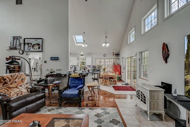 living area featuring a skylight, a high ceiling, and visible vents