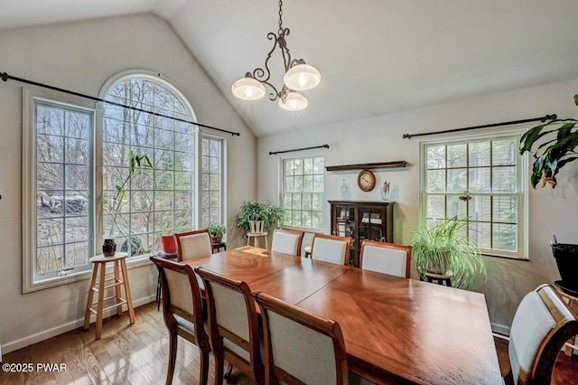 dining room with baseboards, vaulted ceiling, an inviting chandelier, and wood finished floors