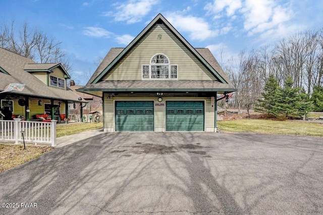 exterior space with aphalt driveway, a lawn, a garage, and roof with shingles