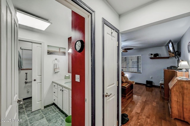 bathroom with vanity, a skylight, baseboards, and wood finished floors