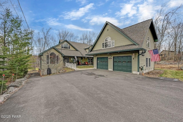 view of front of house with an attached garage, a shingled roof, and aphalt driveway