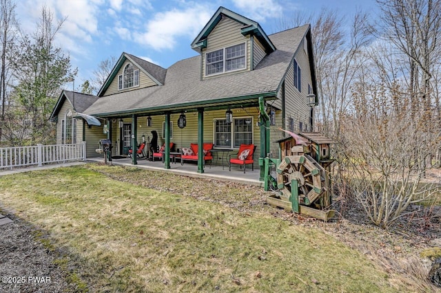 view of front of home featuring a patio area, a front yard, fence, and roof with shingles
