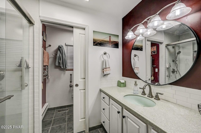 full bathroom featuring vanity, a baseboard heating unit, a stall shower, tile patterned flooring, and backsplash