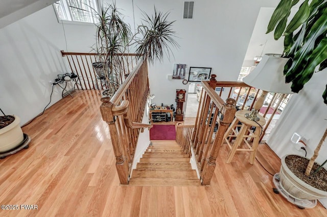 staircase featuring a healthy amount of sunlight, visible vents, and wood finished floors