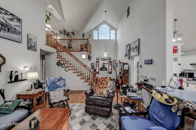 living area with high vaulted ceiling, stairway, and wood finished floors