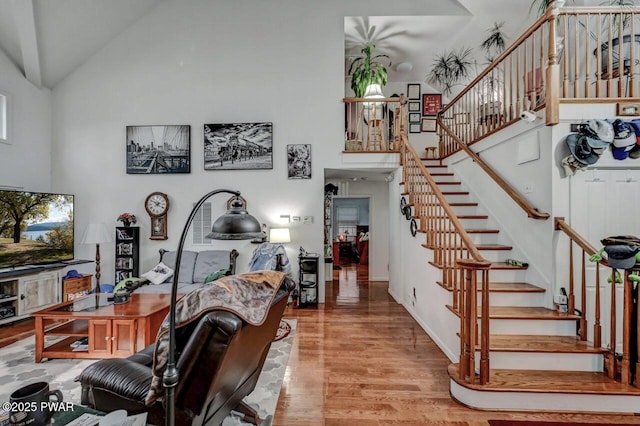 living area featuring high vaulted ceiling, stairway, and wood finished floors