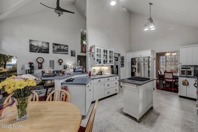 kitchen featuring a peninsula, glass insert cabinets, a ceiling fan, dark countertops, and stainless steel refrigerator with ice dispenser