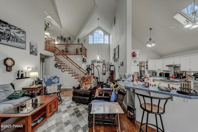 living area featuring high vaulted ceiling, stairway, and wood finished floors