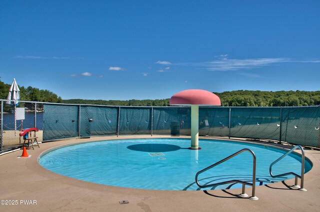 view of pool featuring a wooded view, fence, and a fenced in pool