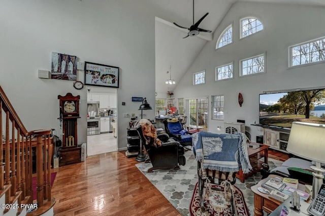 living area featuring a high ceiling, wood finished floors, and ceiling fan