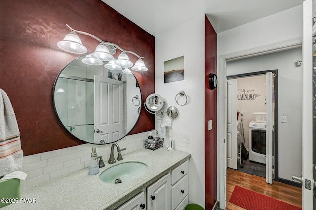 bathroom with vanity, separate washer and dryer, decorative backsplash, and wood finished floors