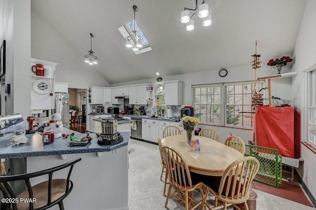 kitchen featuring freestanding refrigerator, stainless steel dishwasher, a peninsula, white cabinetry, and dark countertops