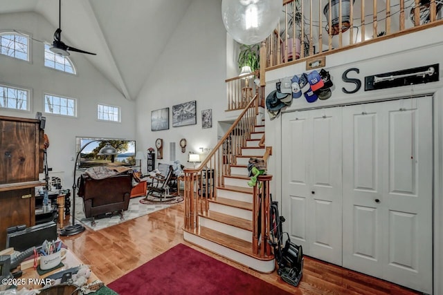 stairs with wood finished floors, high vaulted ceiling, and a ceiling fan