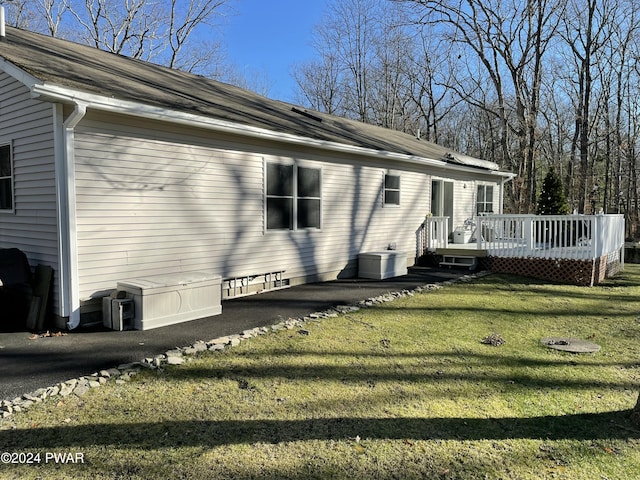 view of property exterior with a wooden deck and a yard