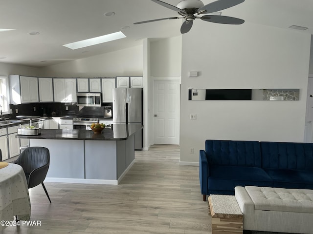 kitchen with backsplash, vaulted ceiling with skylight, white cabinets, and appliances with stainless steel finishes