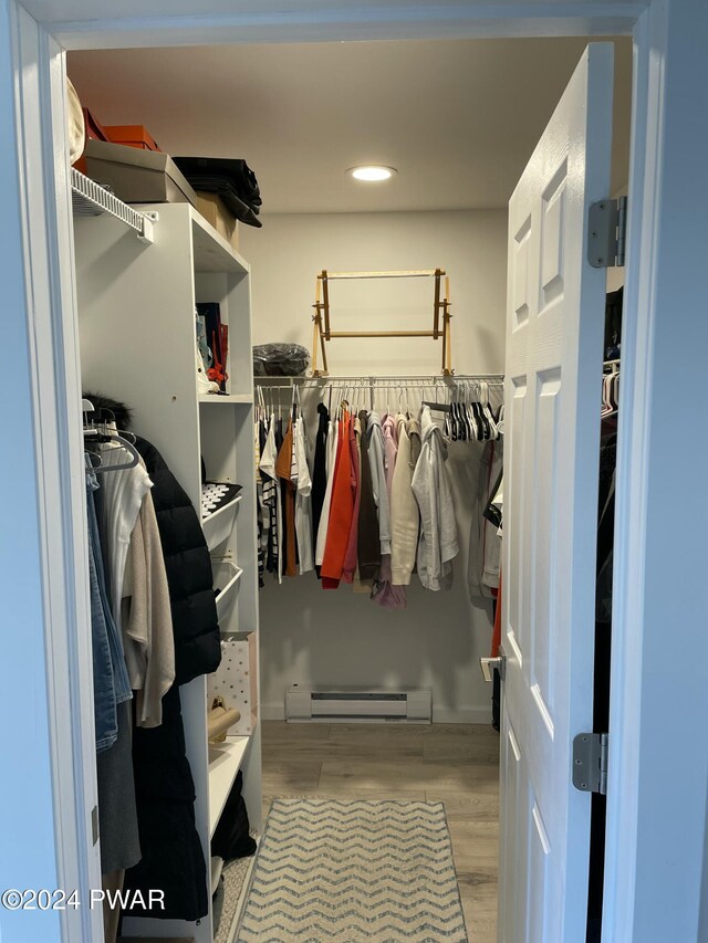 walk in closet featuring a baseboard radiator and light hardwood / wood-style flooring