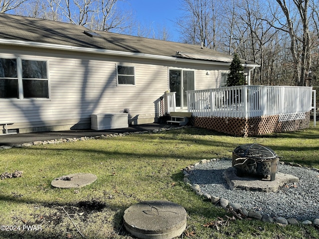 rear view of property with an outdoor fire pit, a lawn, and a wooden deck