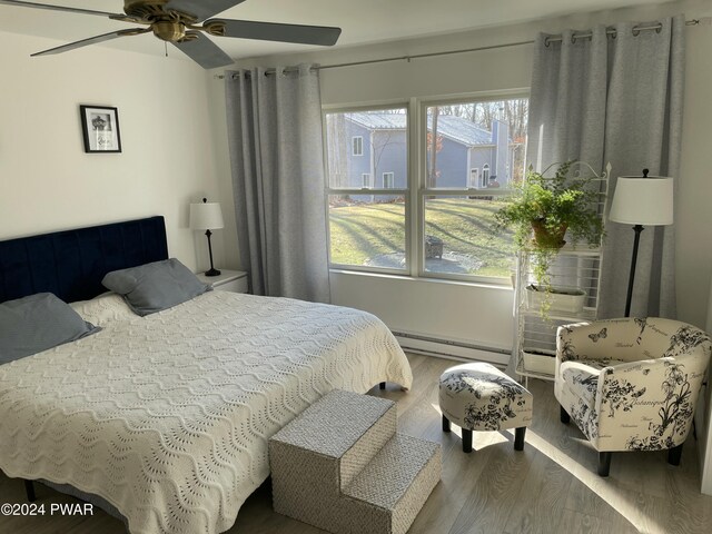 bedroom featuring baseboard heating, ceiling fan, and hardwood / wood-style flooring