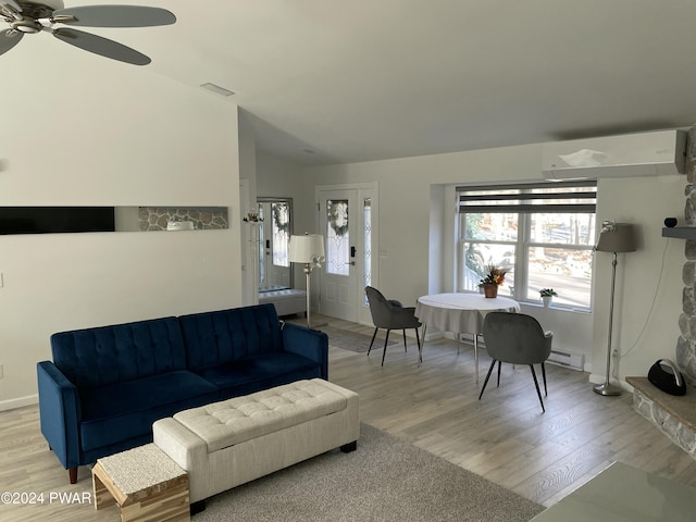 living room with light wood-type flooring, a wall unit AC, baseboard heating, ceiling fan, and vaulted ceiling