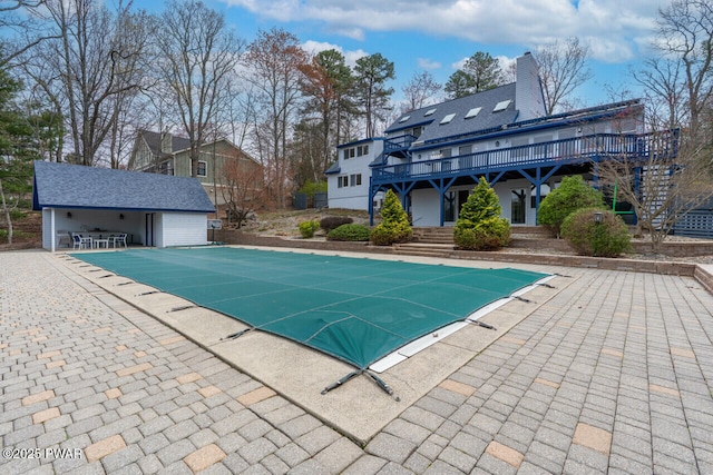 view of swimming pool featuring an outbuilding, a wooden deck, a patio area, stairway, and a covered pool