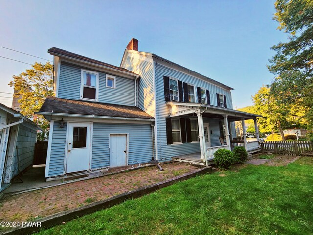 back of house featuring a lawn and a porch