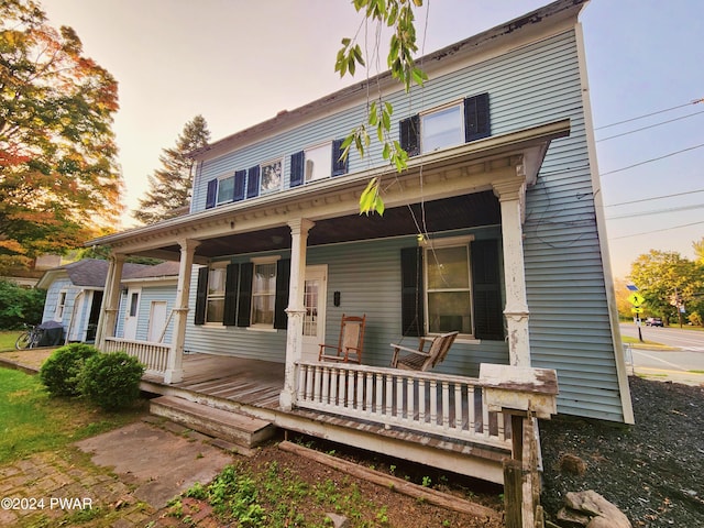 back house at dusk with covered porch