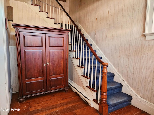 staircase with hardwood / wood-style floors and a baseboard heating unit