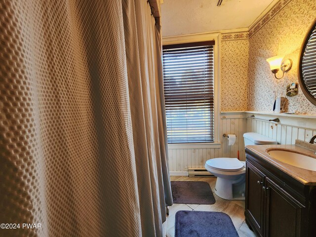 bathroom featuring vanity, baseboard heating, wooden walls, crown molding, and toilet