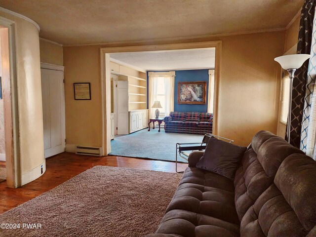 living room featuring built in shelves, crown molding, a baseboard radiator, and hardwood / wood-style flooring