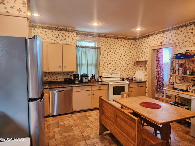 kitchen featuring cream cabinetry, stainless steel appliances, a wealth of natural light, and crown molding