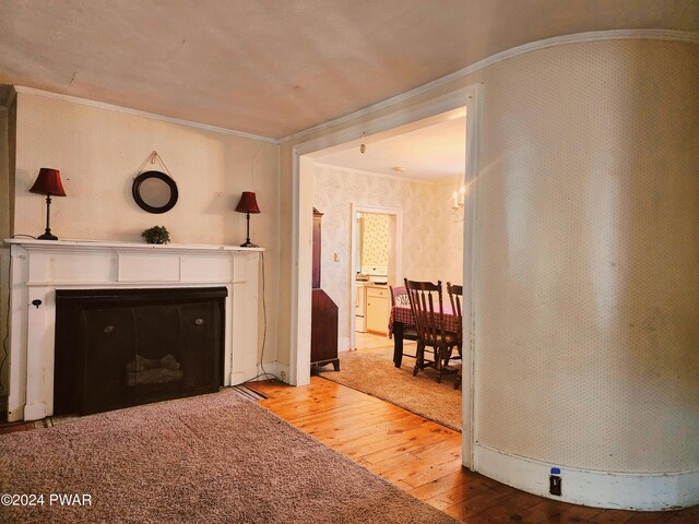 unfurnished living room featuring hardwood / wood-style floors and crown molding