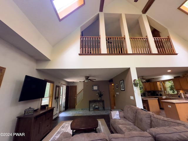 living room with a skylight, high vaulted ceiling, and ceiling fan