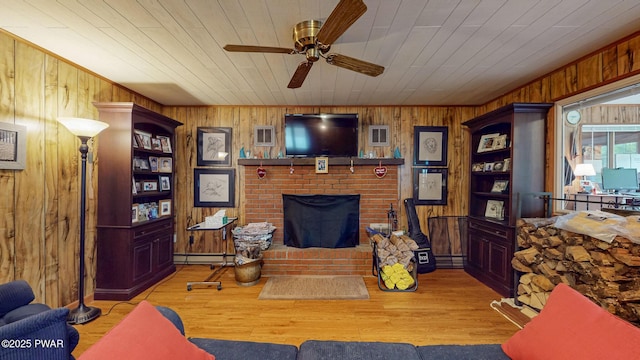 163 Wild Acres Dr, Dingmans Ferry, PA 18328 - living area with a ceiling fan, wood walls, baseboard heating, a brick fireplace, and wood finished floors